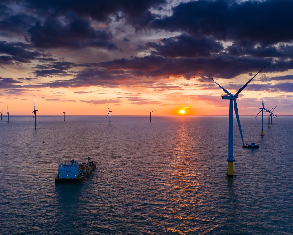 Schepen in windpark bij zonsondergang
